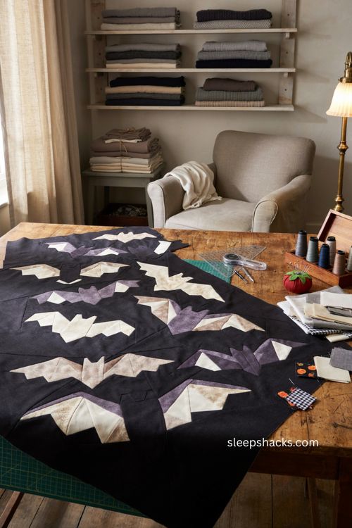 Bat quilt block with black silhouettes on cream gray and navy fabric for moody Halloween quilting