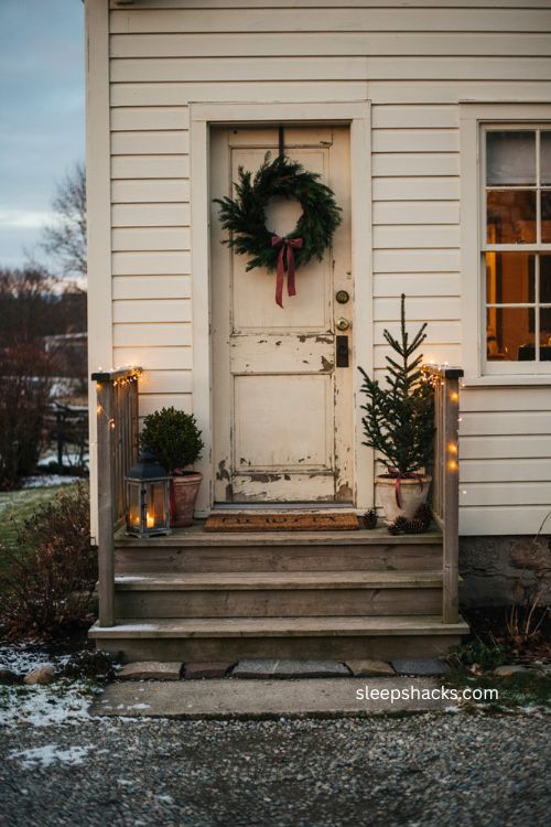Beautiful christmas outdoor entrance with wreath warm lights potted evergreens and lanterns 