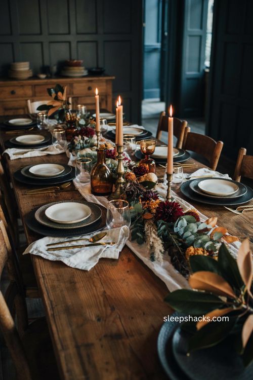 Black and gold Thanksgiving place setting with cream plates gold flatware candlelight and moody fall table decor 