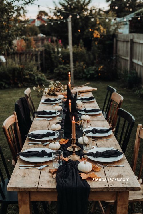 Black and white outdoor Halloween tablescape with witch hats and pumpkins 