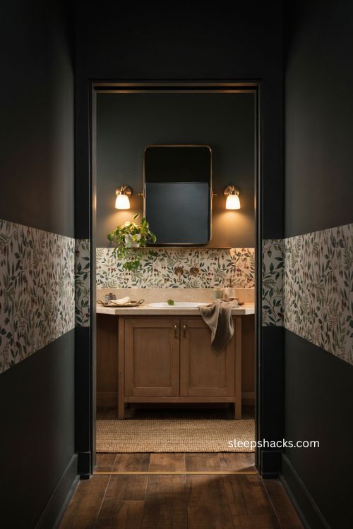 Black bathroom with botanical wallpaper band brass fixtures and mirror