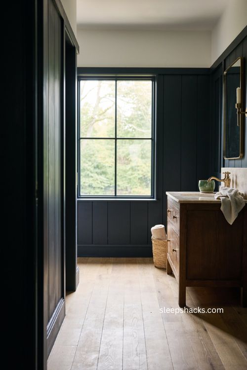 Black bathroom with natural light picture window dark wood and greenery