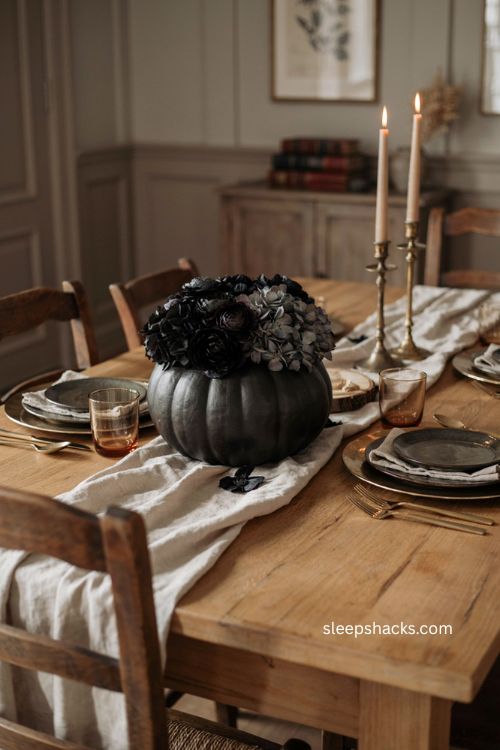 Black flower pumpkin arrangement with dark charcoal blooms for an elegant halloween table 