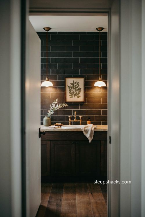 Black powder room with gold pendant lights vertical subway tile and botanical art