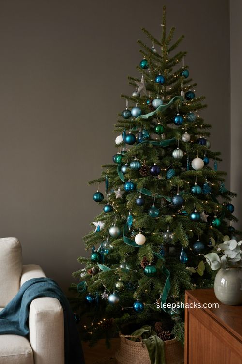 Blue and green Christmas tree with jewel tone ornaments and elegant festive decor 