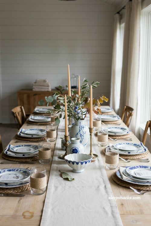 Blue and white coastal Thanksgiving centerpiece with porcelain vases and raffia 