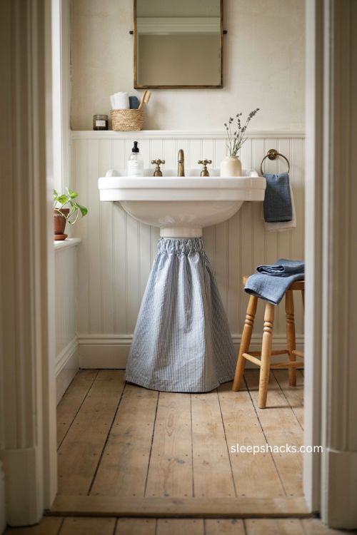 Blue and white ticking stripe sink skirt in a cozy farmhouse bathroom 