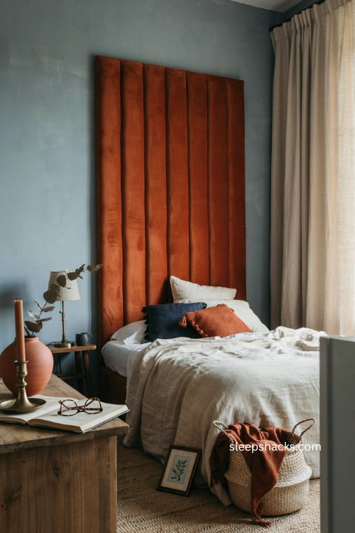 Burnt orange headboard against blue walls with cozy bedroom decor 
