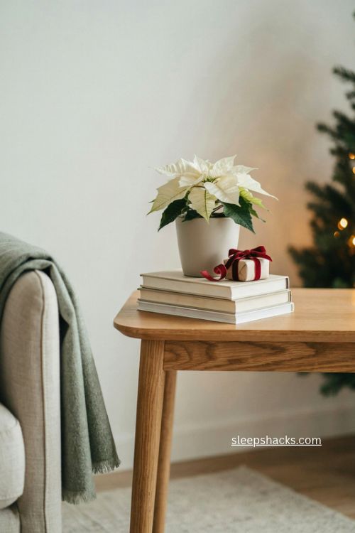 Christmas end table decor with stacked neutral books white poinsettia and red gift 