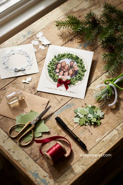 Christmas handmade wreath photo card with family photo green leaves red bow and cozy craft supplies 