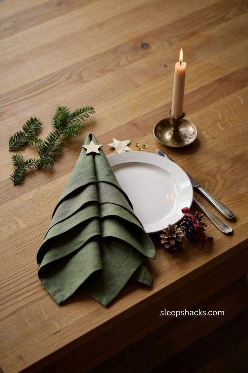 Christmas tree napkin folding with a tiny star topper for holiday table decor 