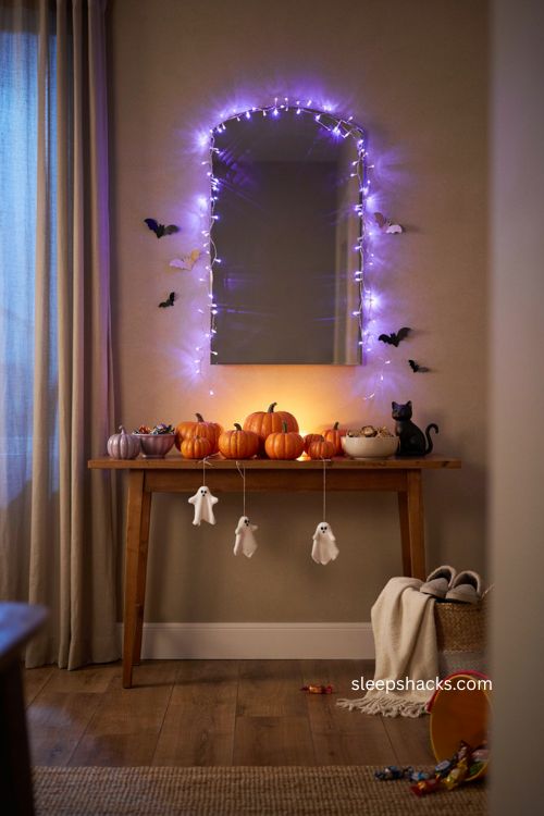 Colorful Halloween entry table with purple string lights glowing pumpkins and ghost decor