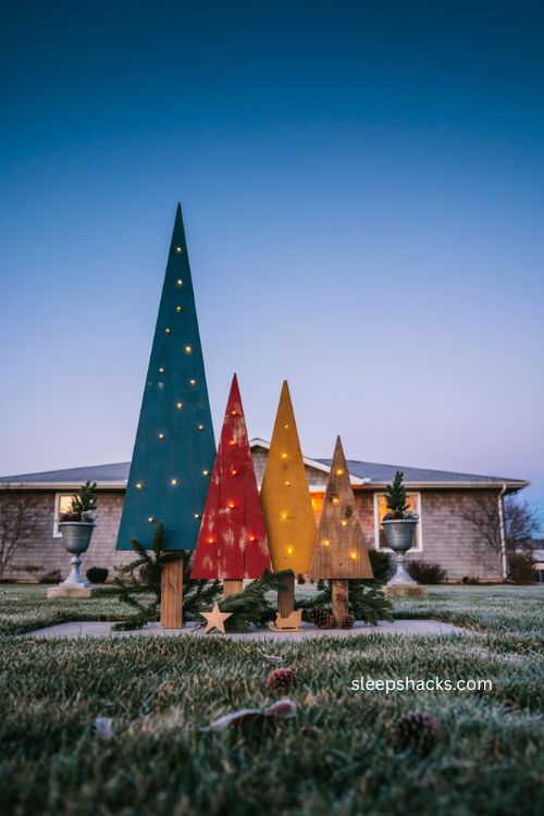 Colorful outdoor wood christmas trees glowing with teal red and mustard lights 