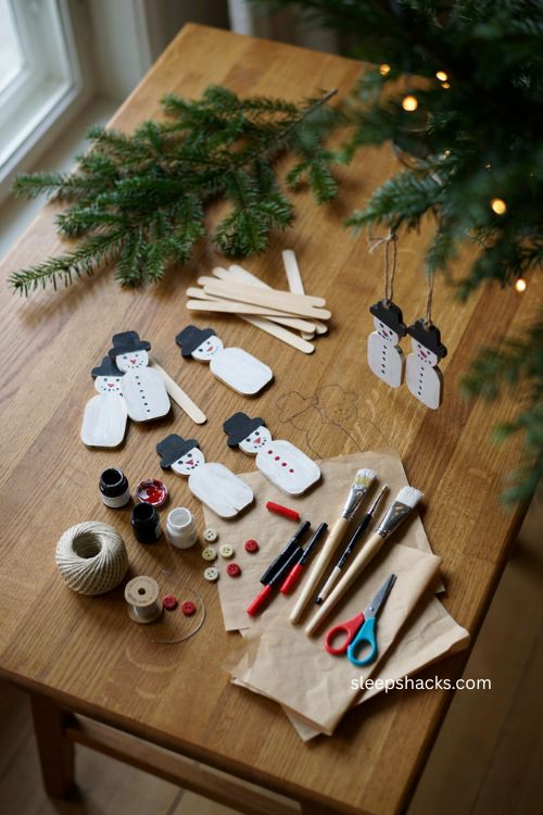 Craft stick snowman christmas ornament for toddlers with painted popsicle sticks black hat buttons and carrot nose 