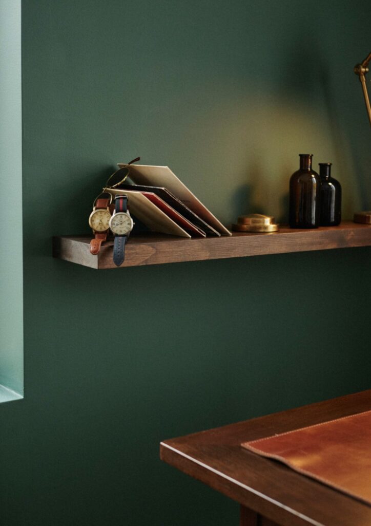 Curated collection of vintage objects on dark walnut shelving in a mens home office 
