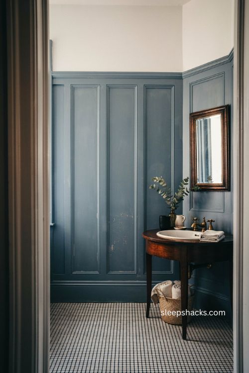 Denim blue tall wainscoting with dark wood and black white tile in a formal bathroom 