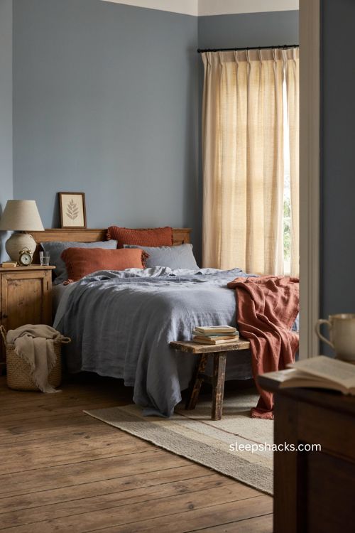 Dusty blue bedroom with soft burnt orange accents and vintage decor 