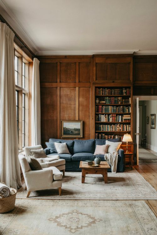 Elegant living room decor with dark wood paneling and soft light accent furniture 
