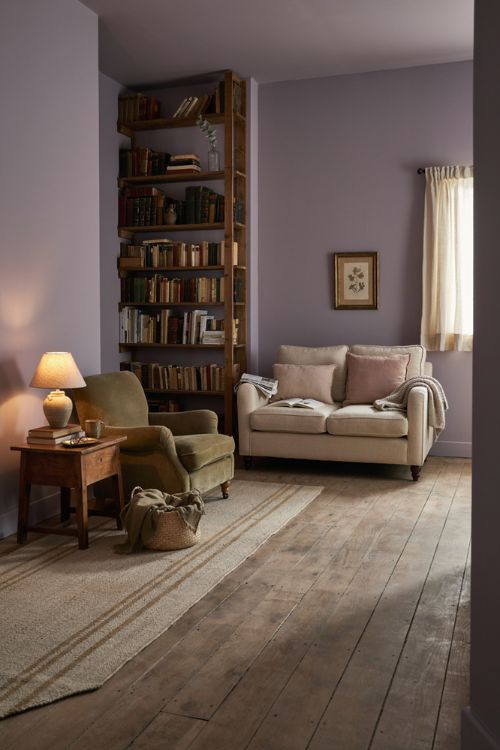 Elegant living room decor with unexpected dusty lavender green walls and cozy vintage furniture 