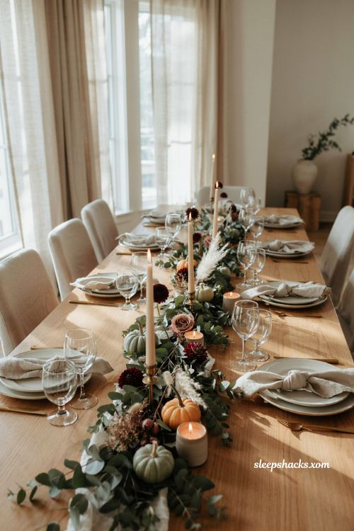Eucalyptus and maroon Thanksgiving tablescape with burgundy flowers pumpkins and greenery runner

