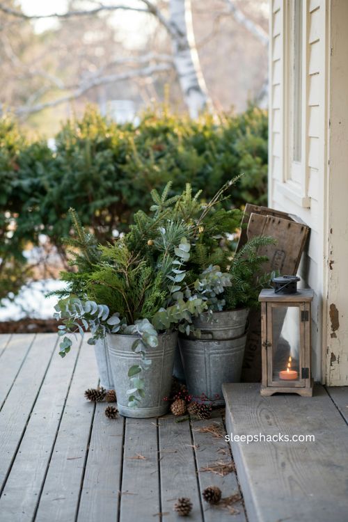 Farmhouse Christmas porch with galvanized buckets and mixed greenery 