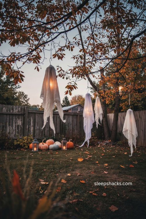 Ghostly fabric spirits floating in trees for backyard Halloween party decorations 