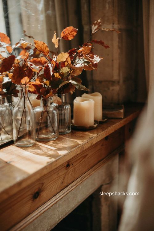 Glass vases filled with colorful fall leaves on a mantle 
