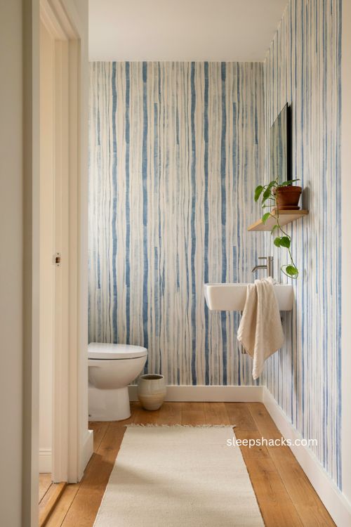 Graphic blue striped wallpaper with white fixtures in a modern contemporary bathroom 