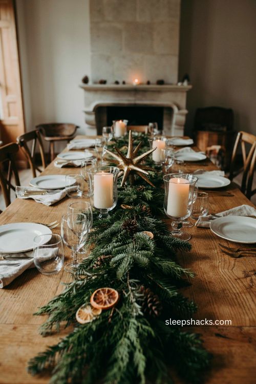 Green Christmas table with gold starburst centerpiece and cream candle hurricanes 