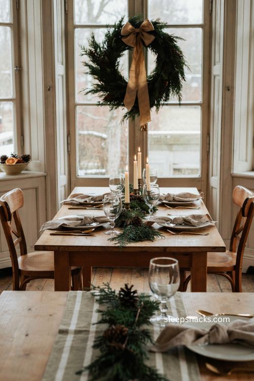 Green Christmas wreath with gold bow behind an elegant dining table 