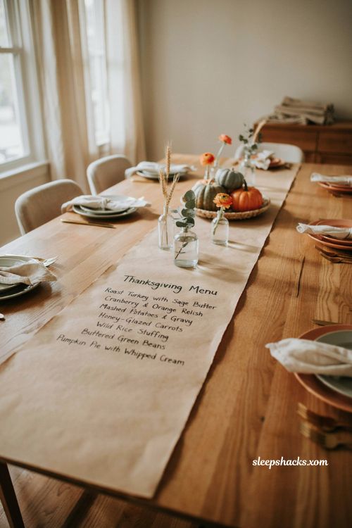 Handwritten Thanksgiving menu on butcher paper runner with pumpkins candles and farmhouse table decor 