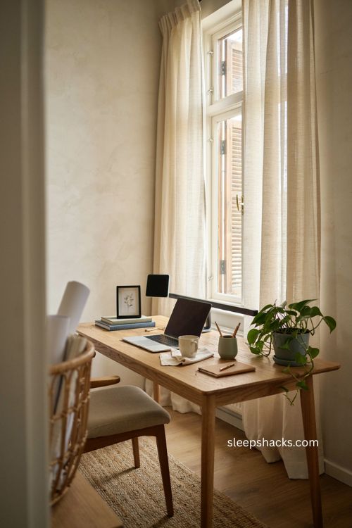 Home office setup with natural light desk by window and linen curtains 