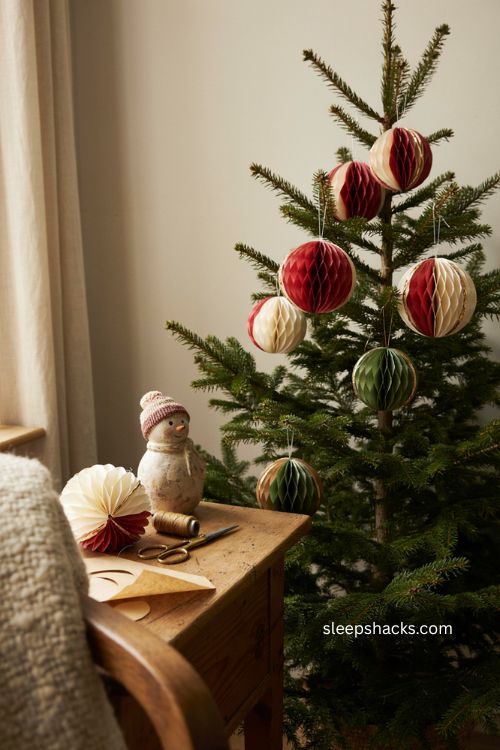 Honeycomb paper ornaments with layered folded scrapbook paper and gold painted edges on a cozy christmas tree 