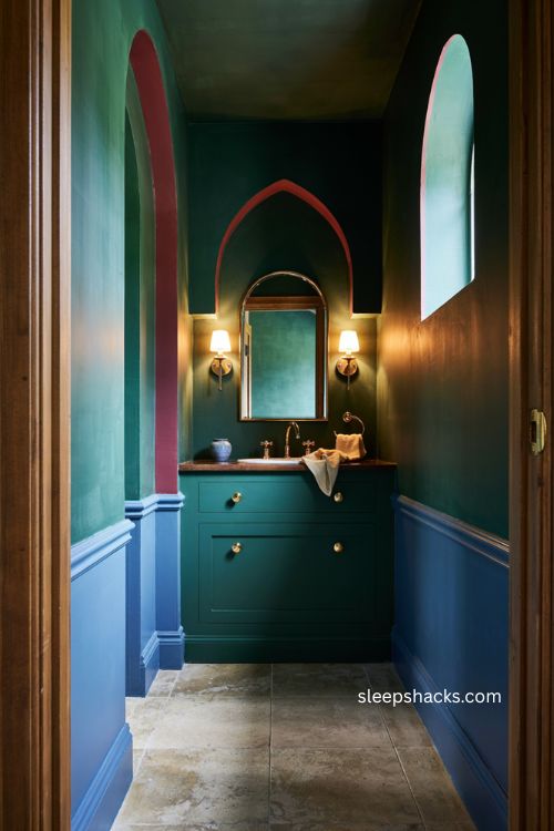 Jewel tone moody bathroom with emerald walls brass fixtures arched mirror and vintage glamour 