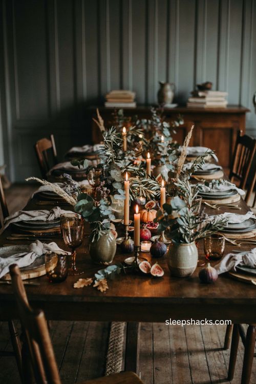 Layered greenery Thanksgiving centerpiece with eucalyptus olive branches trailing ivy candles pumpkins and rustic fall decor 