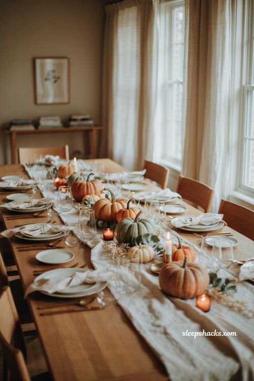 Layered pumpkin Thanksgiving centerpiece with orange white and pale green pumpkins on a dining table
