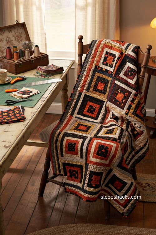 Log cabin Halloween throw with orange black rust and gray quilt blocks in cozy sewing room