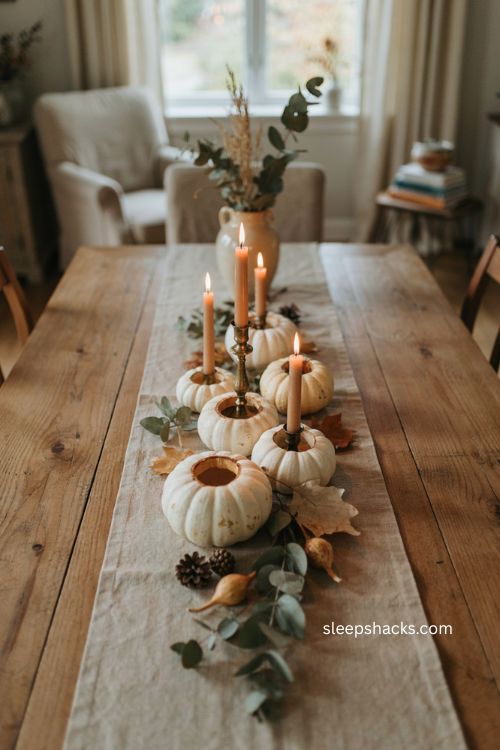 Mini pumpkin candle holders with white gourds and elegant cozy autumn table centerpiece 