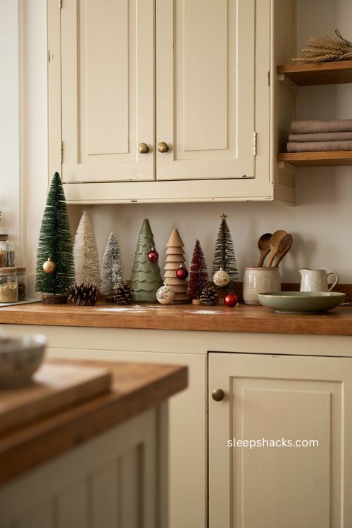 Miniature Christmas trees lined up above kitchen cabinets 
