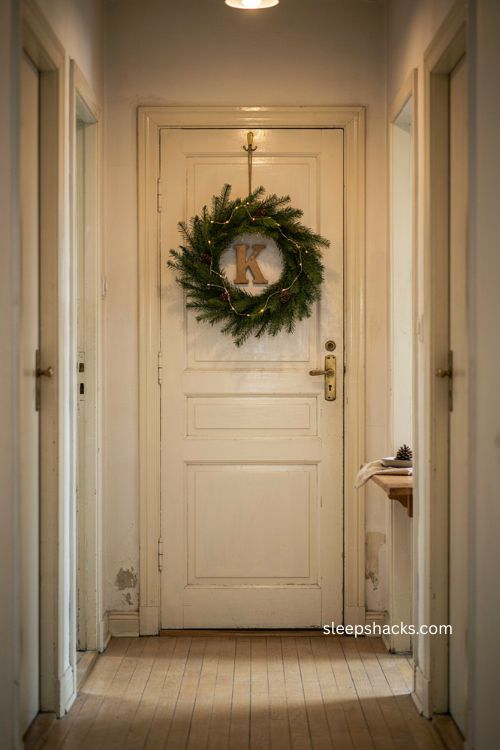 Monogrammed apartment door christmas decor with greenery wreath and warm fairy lights 