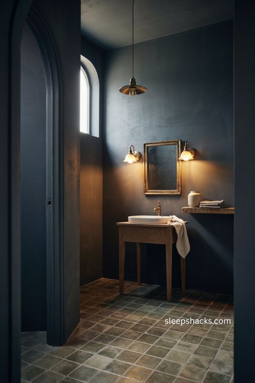 Moody bathroom lighting with warm sconces dark walls vintage vanity and cozy glowing atmosphere 