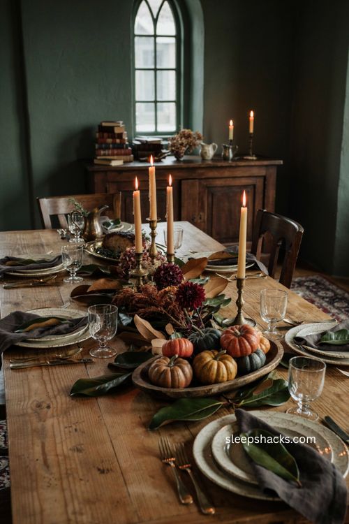 Moody thanksgiving tablescape with burgundy forest green magnolia leaves aged brass candles and rustic vintage table decor 