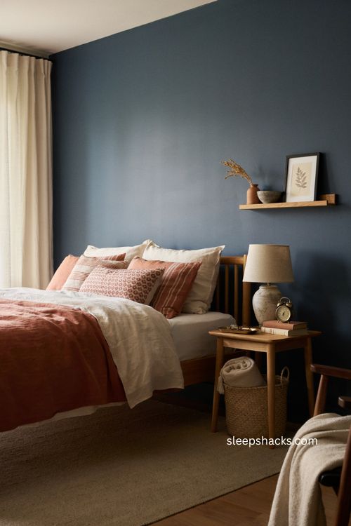 Navy walls behind burnt orange bedding in a cozy bedroom 