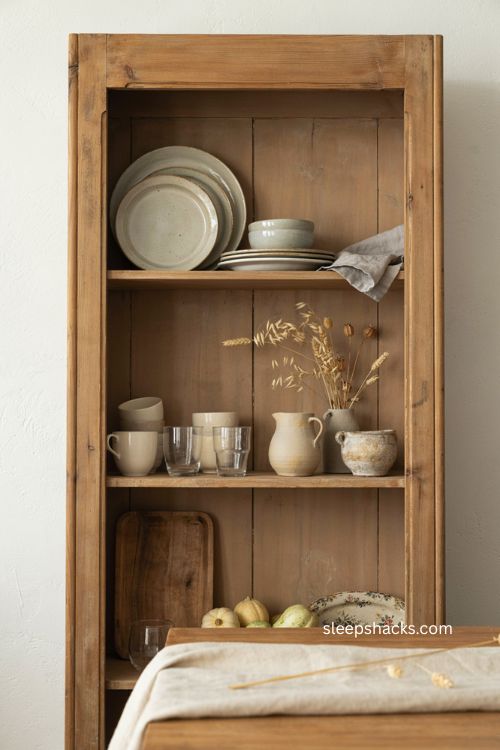 Neutral fall dining room hutch with vintage dishes gourds dried stems and pottery