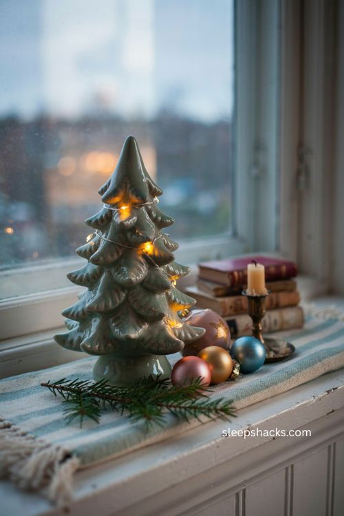 Nostalgic ceramic light up Christmas tree on windowsill with vintage glaze soft glow and cozy holiday decor 