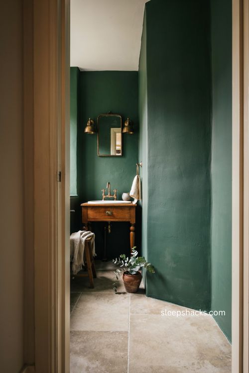 One bold element moody bathroom with forest green walls simple wood vanity and balanced vintage design 
