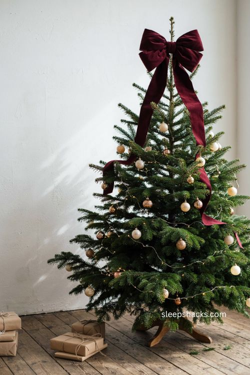 Oversized velvet bow topper on Christmas tree with long ribbon tails 