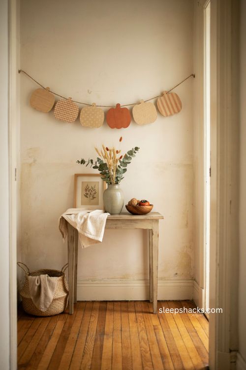 Patterned wooden pumpkin banner with felt balls over a rustic Thanksgiving entryway table
