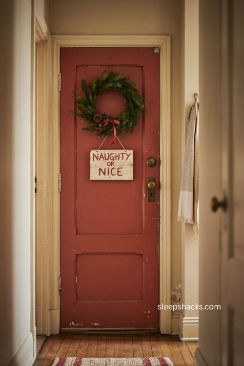 Playful naughty or nice christmas sign on apartment door with wreath and natural greenery 