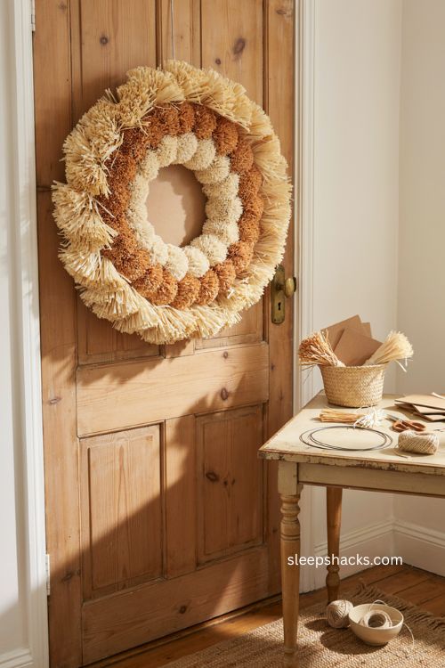Raffia ring wreath Thanksgiving door decor with layered natural fibers and playful pom pom texture 